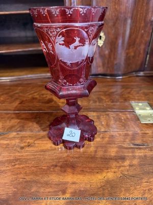 un vase rouge posé sur une table en bois, sur laquelle se trouve une étiquette