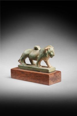 une statue en bronze représentant un lion, posée sur un socle en bois