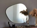 a mirror on the wall above a table with a vase of flowers