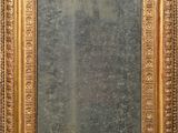 an antique gold framed mirror with ornate design on a wall