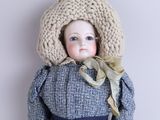 doll with blue eyes wearing a knitted hat and blue dress
