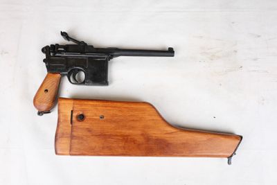 un gros plan d'un pistolet posé sur une surface blanche, avec un étui en bois