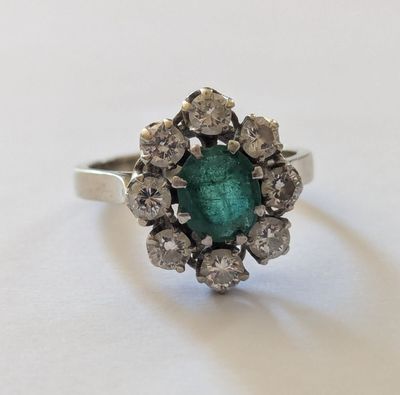 gros plan d'une bague avec une pierre verte entourée de diamants blancs