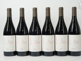 six bottles of wine are lined up in a row on a white surface