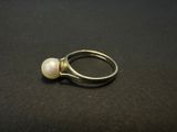 a close up of a pearl ring on a black surface