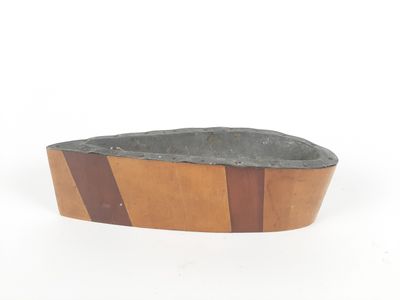 a wooden bowl with a stone in it on a white surface
