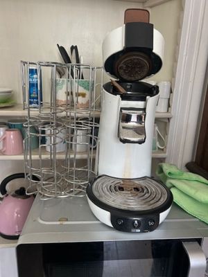 a coffee maker sitting on top of a microwave in a kitchen
