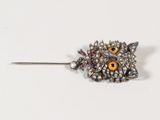 une image représentant une broche en forme de chouette avec des yeux jaunes sur la tête