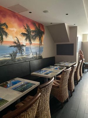 des tables et des chaises dans un restaurant dont le mur est orné d'une fresque représentant des palmiers