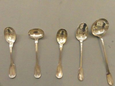six cuillères en argent sont alignées les unes à côté des autres sur une table
