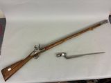 un vieux fusil avec une crosse en bois et un couteau posés sur une table