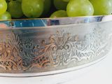 a silver bowl filled with green grapes on top of a table