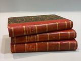 three red books stacked on top of each other on a table