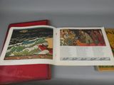 an open book sitting on top of a table next to a red book