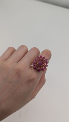 quelqu'un tient dans sa main une bague en forme de fleur violette