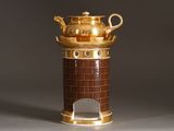 a gold teapot on a stand on a gray surface