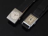 two watches sitting next to each other on a black surface
