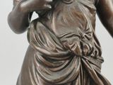 bronze statue of a woman holding a flower in her right hand