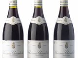 three bottles of wine are lined up on a white surface