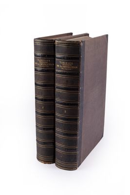 two old books sitting on top of each other on a white surface
