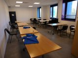 une pièce avec des tables et des chaises, et une chemise bleue posée sur la table