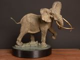 statue of an elephant with tusks standing on a wooden table