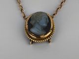 a close up of a necklace on a white surface with a gold chain