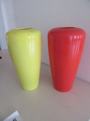 des vases jaunes et rouges posés côte à côte sur une étagère blanche