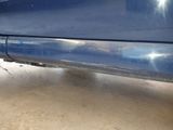 the rear end of a blue car with a flat tire in a garage