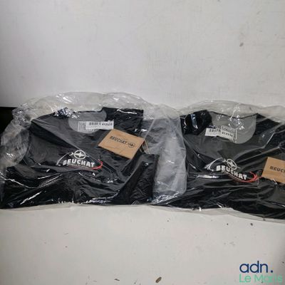 trois t-shirts noirs emballés dans du plastique, posés sur une table