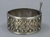 an old silver bracelet with a bird on it on a table