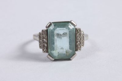 un gros plan d'une bague posée sur une surface blanche, ornée d'une pierre verte