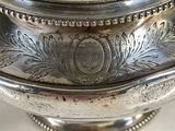 a silver bowl with a lid on a white table