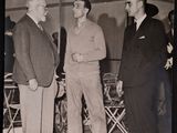 black and white photograph of three men in suits talking to each other