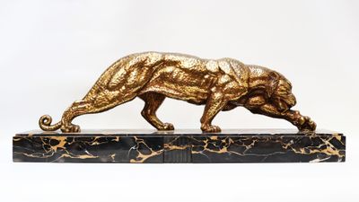 a gold statue of a tiger on a marble base