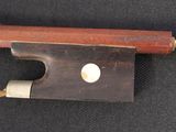 an old violin bow with a wooden handle on a black surface