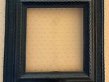 a black picture frame hanging on a wall next to a white wall