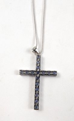 un gros plan d'une croix posée sur une surface blanche, avec une chaîne
