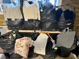 many bags of clothes sitting on a bench in a room