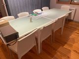 a glass table with white chairs and a laptop on it