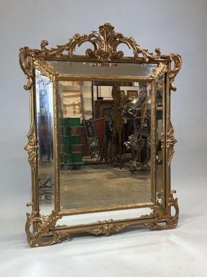 une image représentant un miroir à cadre doré posé sur un sol blanc