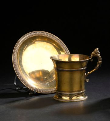 une coupe en or et un plat en argent posés sur une table