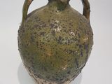 un vase vert posé sur une surface blanche