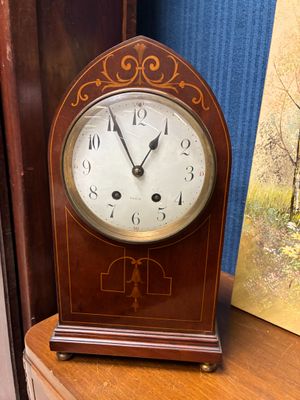 une horloge en bois posée sur une étagère à côté d'un tableau