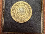 an old book with a gold medallion on it sitting on top of a wooden table