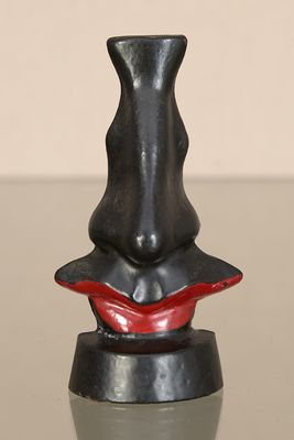 un vase noir au bord rouge posé sur une table en verre