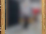 un miroir à cadre doré posé sur une table à côté d'une horloge