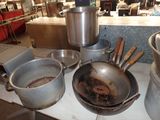Plusieurs casseroles et poêles sont posées sur une table dans une cuisine.
