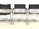 trois fauteuils en cuir noir placés les uns à côté des autres sur un sol blanc