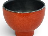 a red bowl with a black rim on a white background